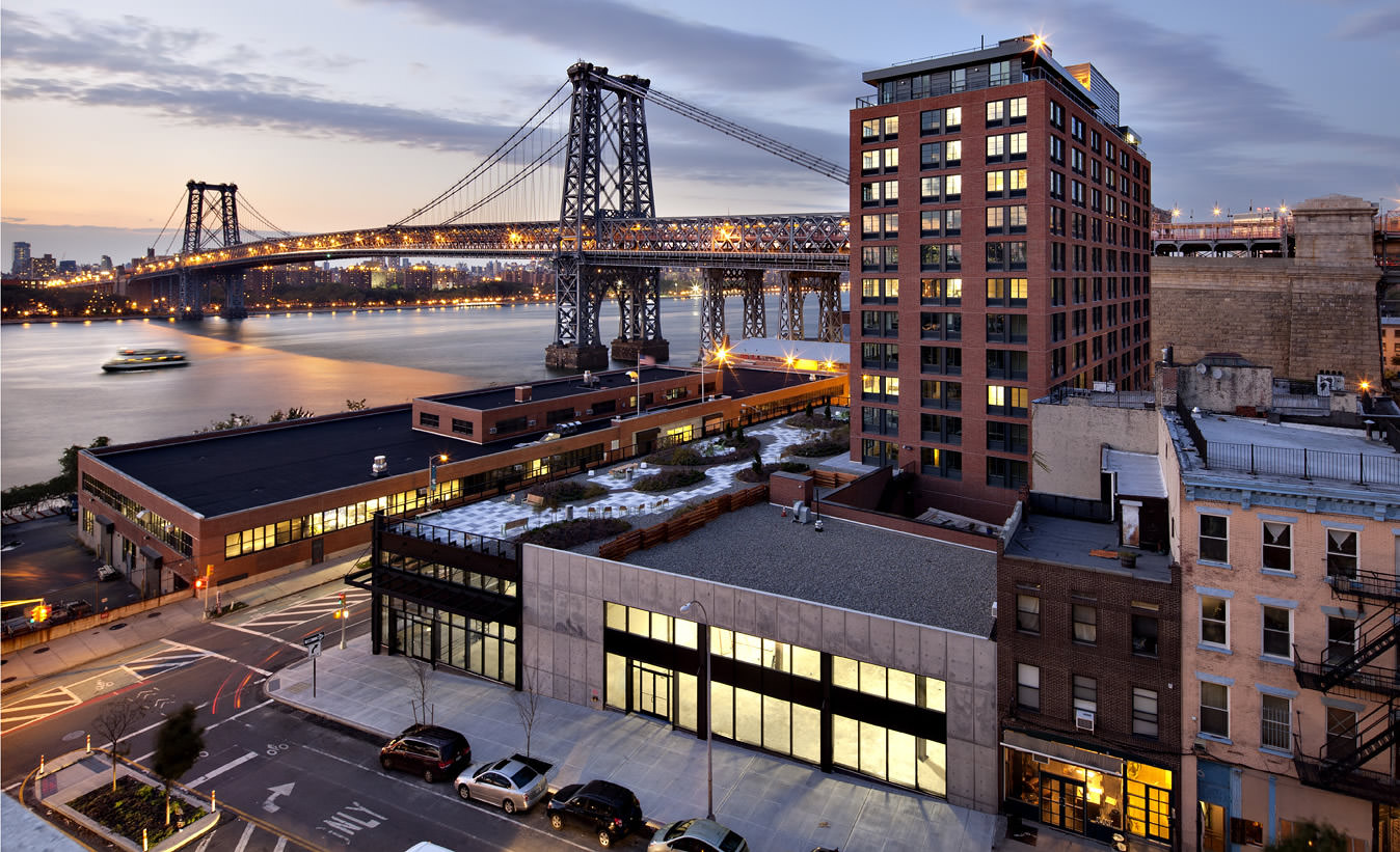Aerial view of modern urban apartment buildings near a suspension bridge, managed by the Best Property Management Companies.