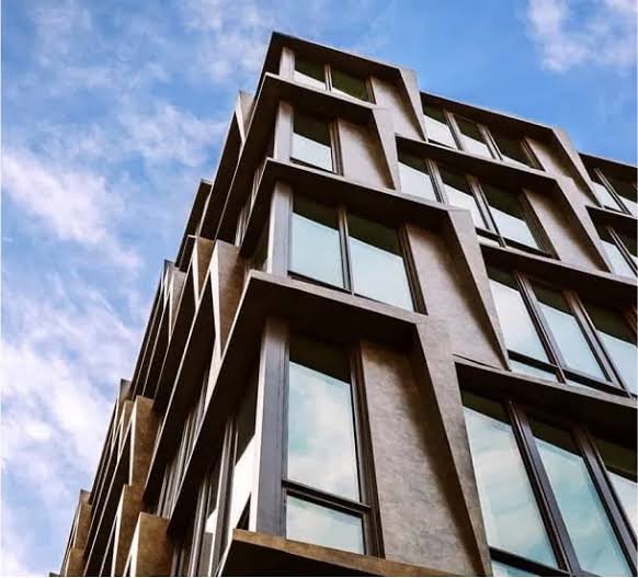 Low-angle view of a modern apartment building with geometric architectural details, representing expert Real Estate Management NYC services.