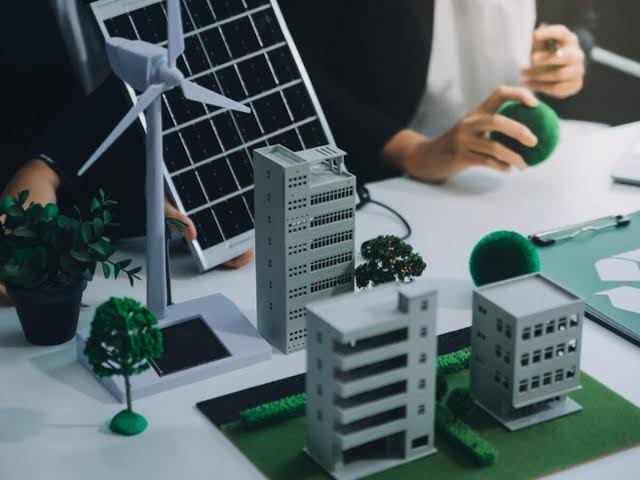 Architectural building models, a solar panel, and a wind turbine showcasing sustainable Residential Building Management.