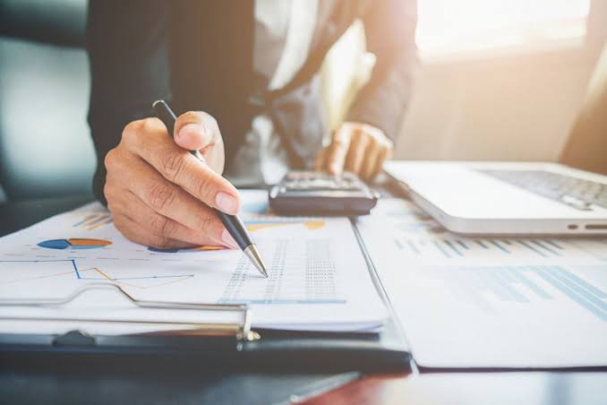 Professional analyzing financial charts and using a calculator at a desk for Property Financial Management.