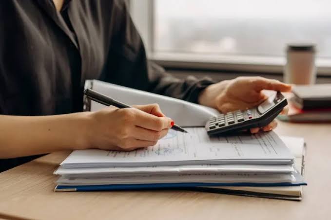 A property manager using a calculator and pen to review financial documents and balance ledger statements, executing professional Rental Property Accounting.